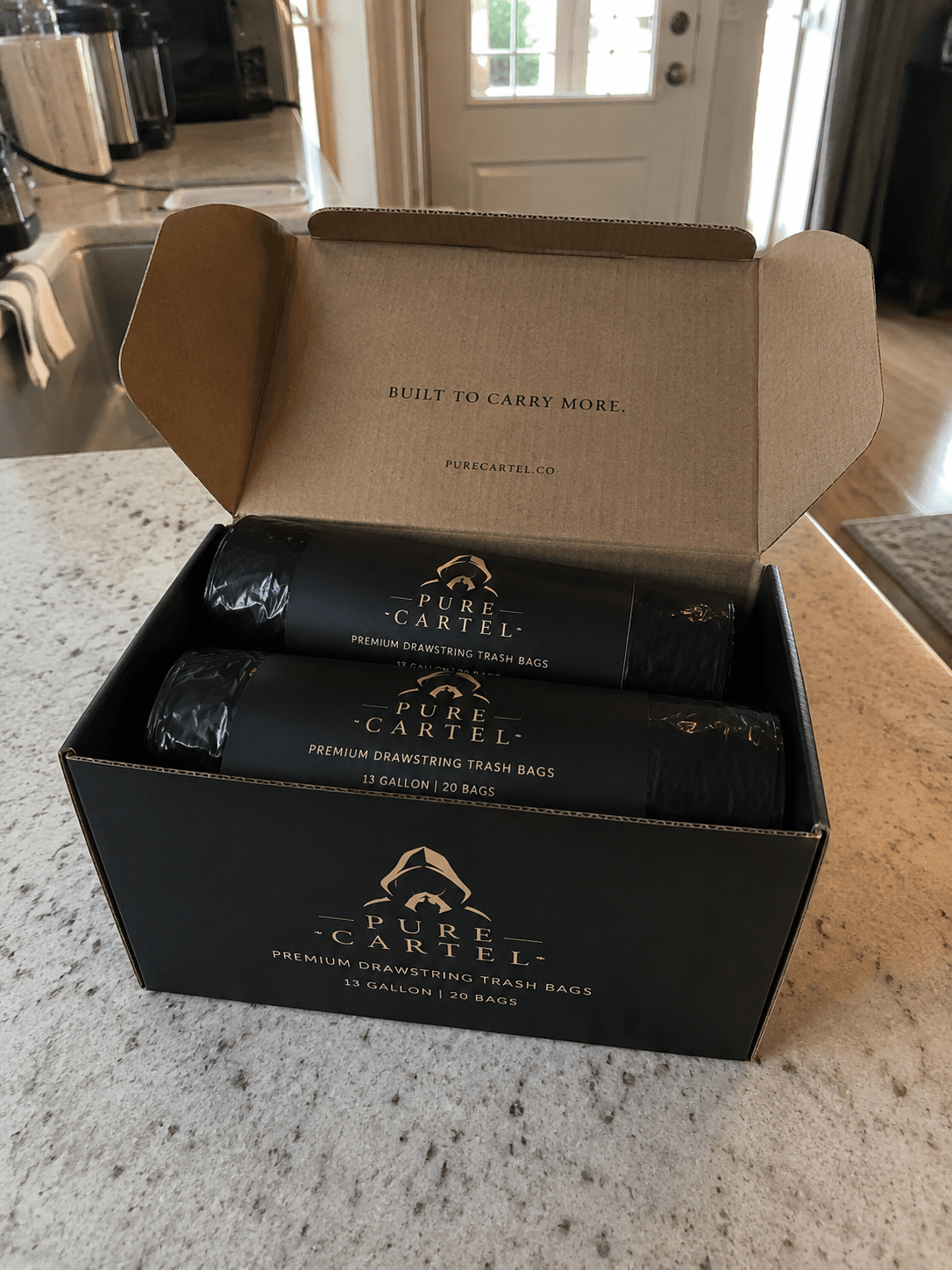 Unboxing two rolls of Pure Cartel bags on the kitchen counter